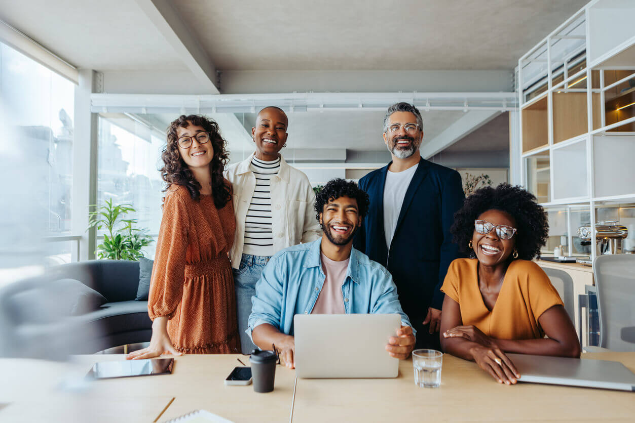 Equipe diversa sorrindo em ambiente corporativo, simbolizando empresas alinhadas à Lei 14.831 de promoção da saúde mental no trabalho