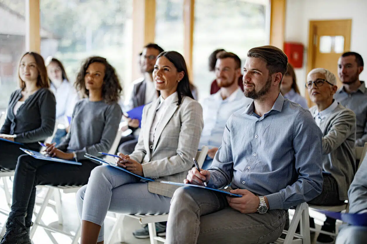 Colaboradores atentos e sorrindo durante eventos corporativos, representando estratégias de engajamento em ações internas da empresa.