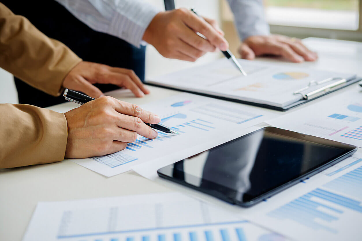 Profissionais analisando gráficos e documentos em uma mesa de reunião, representando a preparação de empresas para fiscalizações trabalhistas por meio de relatórios e checklists de conformidade.