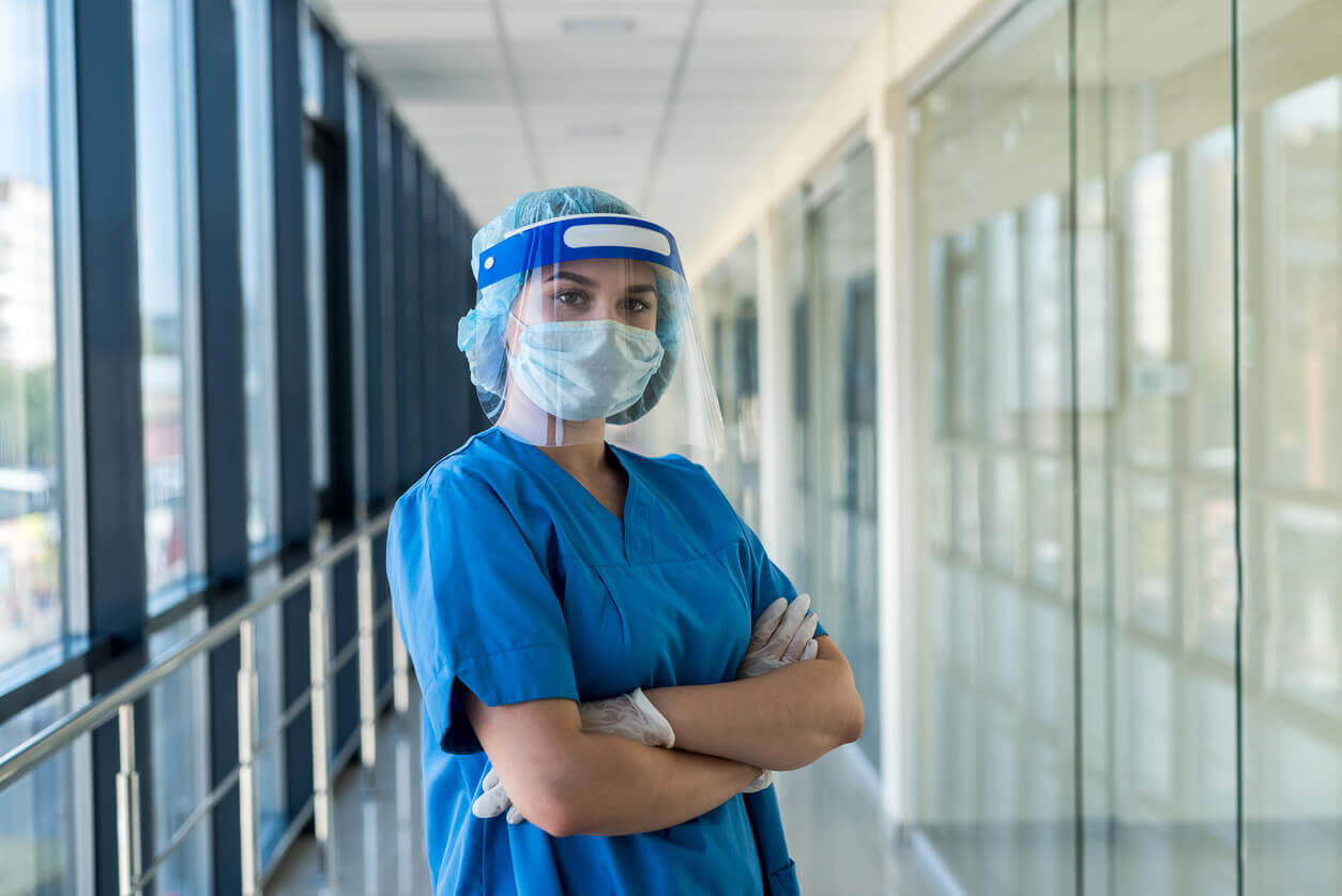 Profissional da saúde utilizando equipamentos de proteção individual em corredor hospitalar, exemplificando a aplicação das normas de SST no ambiente de trabalho.