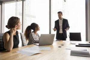 Profissional em reunião com equipe explicando orientações sobre o cumprimento da NR 1 e a importância da conformidade nas normas de segurança do trabalho