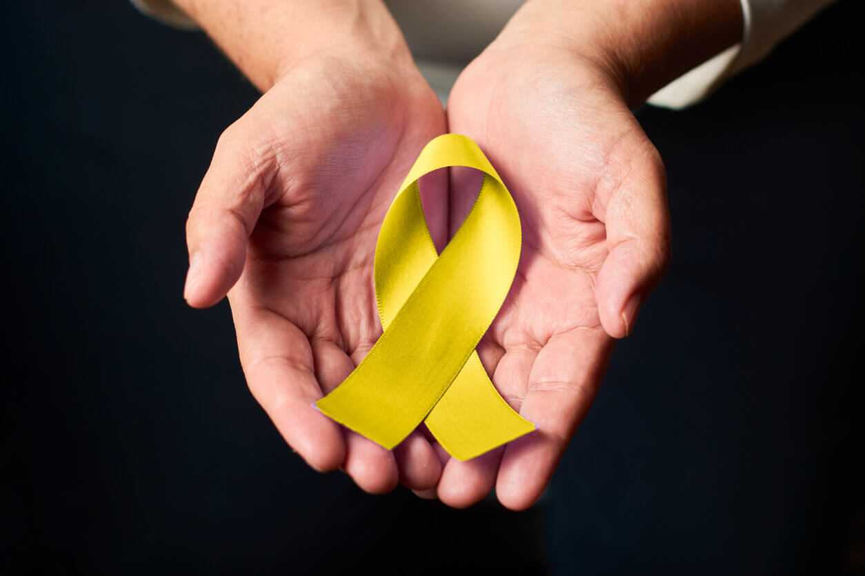 Mãos segurando laço amarelo, símbolo do Setembro Amarelo e da conscientização sobre saúde mental e risco ocupacional nas empresas.