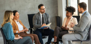 Profissionais em roda de conversa durante uma reunião, representando o processo de avaliação psicológica corporativa para entender o perfil comportamental e promover o bem-estar no ambiente de trabalho.